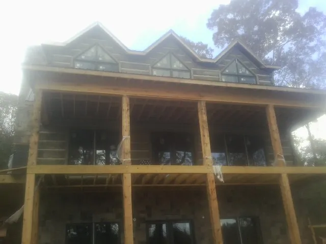 Dormers and porch framing on a large log home under construction — Roof Coating work by our crew in Ville Platte