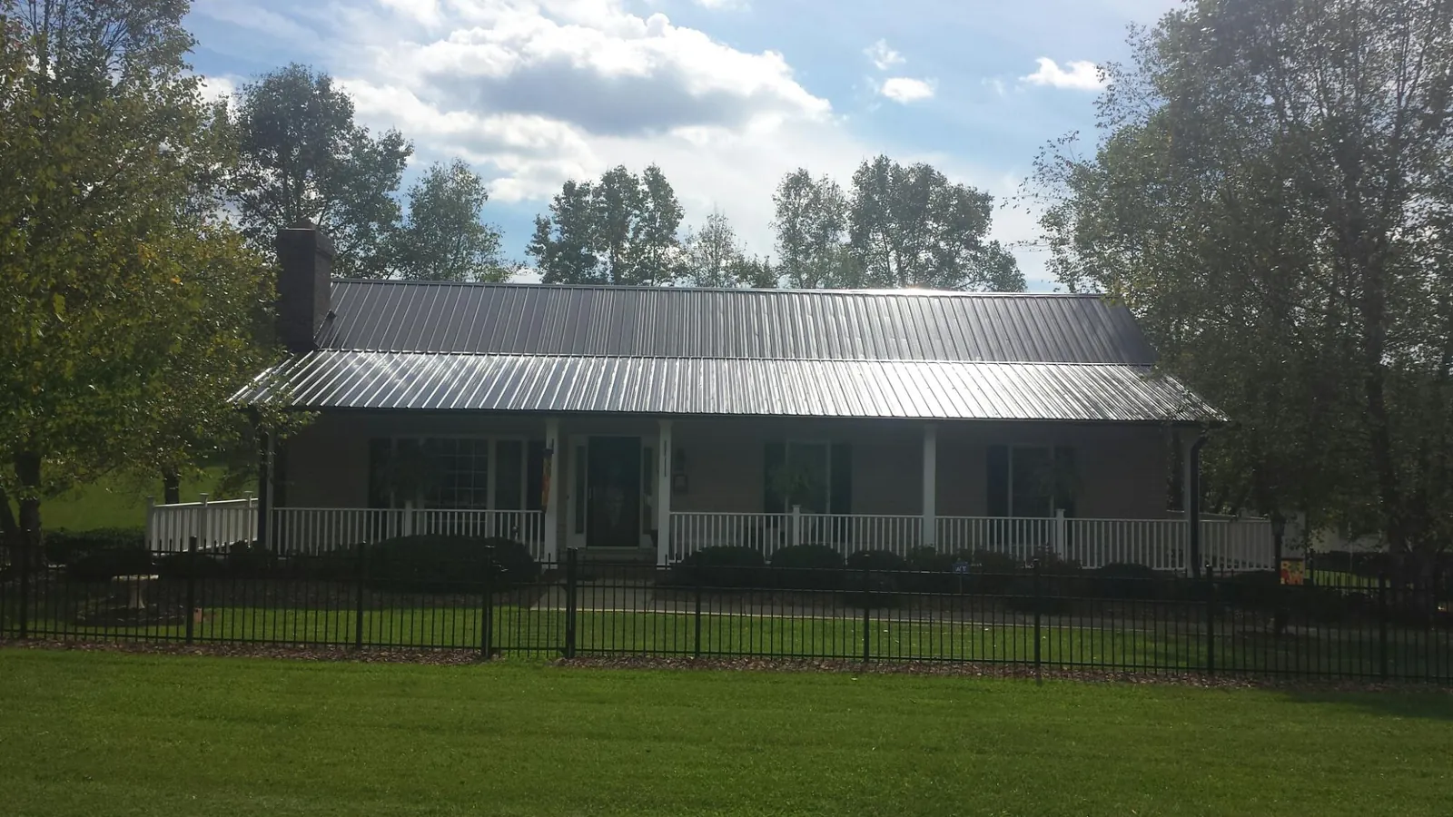 Gray metal roof on a brick ranch with a full width front porch — Gutter Guard Installation work by our crew in Ville Platte
