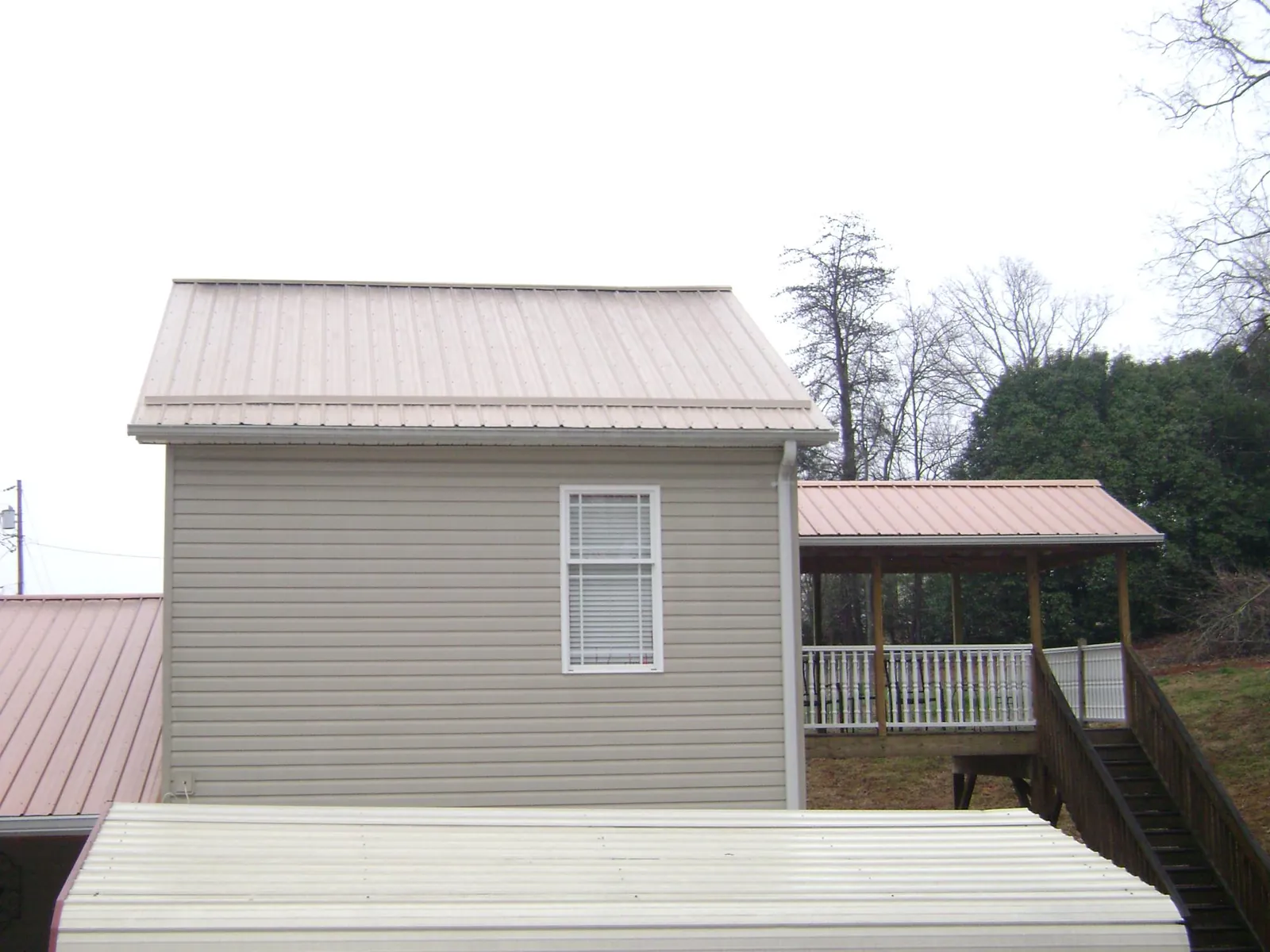 Tan metal roofs on a two story addition and attached porch, from a Roof Replacement job in Ville Platte