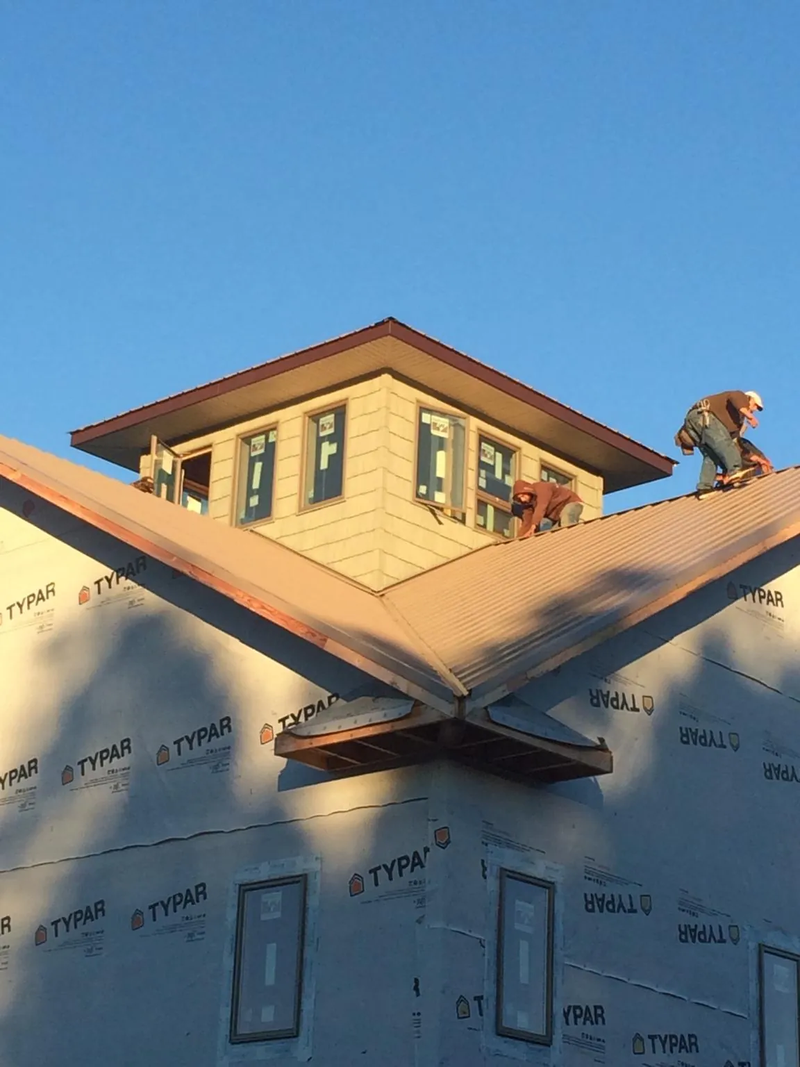 Roofers working around a rooftop cupola on a new metal roof at sunset — Roof Waterproofing in Ville Platte by Roofing Brothers